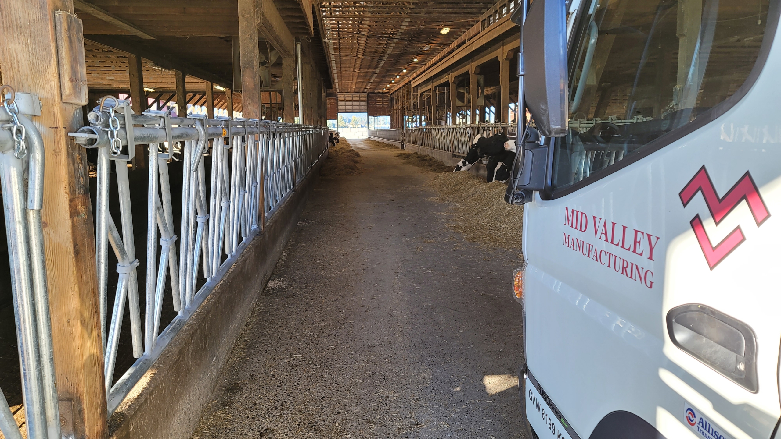 Mid Valley Manufacturing truck parked inside a dairy cow barn.