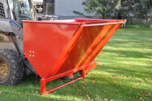 A new red sawdust blower is attached to a skid steer loader.